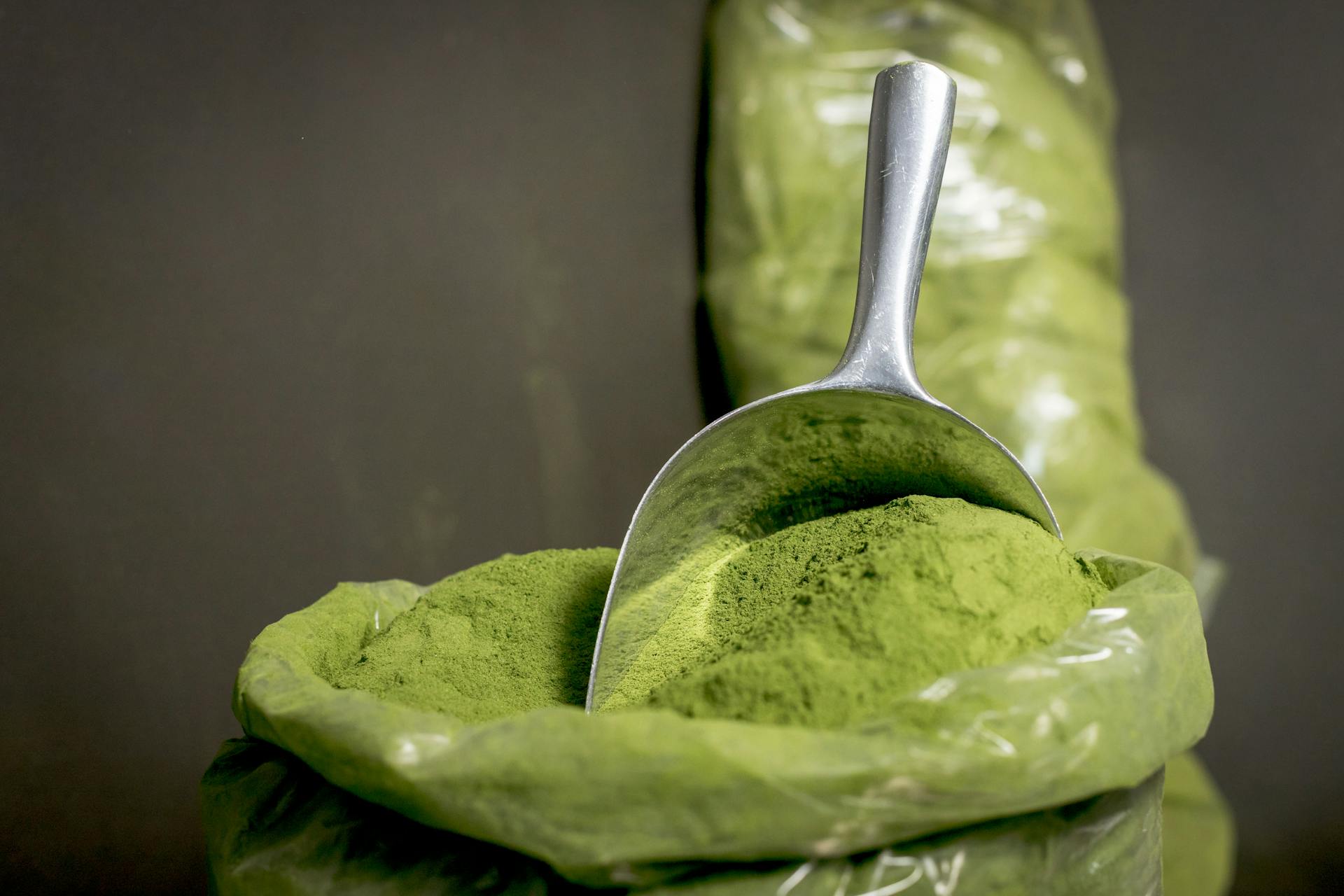 A large metal scoop in a bag of kratom